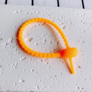 Makroaufnahme von flexiblem orangefarbenem Silikon-Kabelbinder mit verstellbarem Design