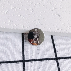 Close-up of polished metal pendant with Keep Calm and Kill Zombies stamped text engraving