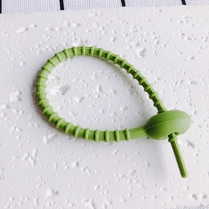 Detail eines verstellbaren avocadogrünen Silikon-Kabelbinders mit Segmentierung und Schnalle