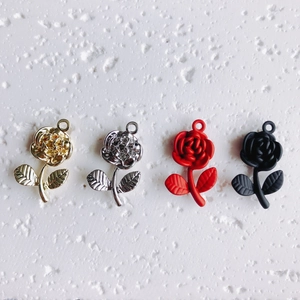 Detalle de cuatro colgantes de rosas en oro, plata, rojo mate y negro para bisutería