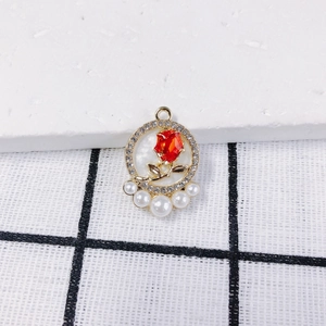 Detail der roségoldenen Anhänger mit rotem Kristall und eleganten weißen Perlen
