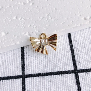 Makroaufnahme Goldener Schleifenanhänger mit Zirkonia-Inlay und detaillierter Faltenstruktur
