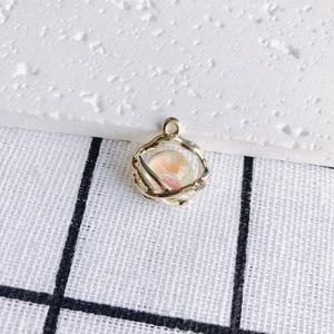 Macro detail of bird's nest gold pendant with peach resin bead and tiny zircon stone