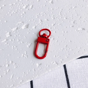 Détail d'un fermoir mousqueton en métal rouge peint avec anneau rotatif pour bijoux DIY