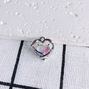 Detail of silver heart pendant with iridescent purple stone and small white pearl