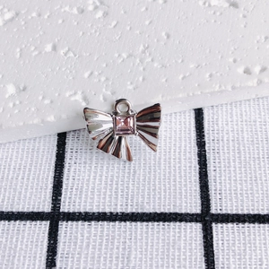 Nahaufnahme eines silbernen Schleifenanhängers mit rosa Zirkon für DIY-Schmuckdesign