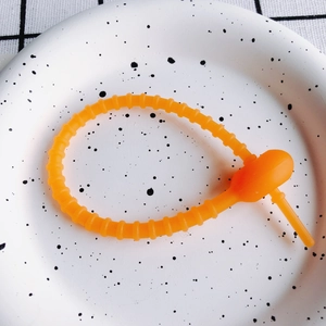 Nahaufnahme eines orangefarbenen Silikon-Kabelbinders mit rutschfester Textur auf Teller