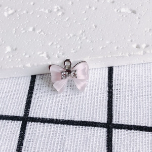 Makroaufnahme eines rosa Schleifenanhängers mit Zirkonia-Inlay und Metallring für DIY-Schmuck