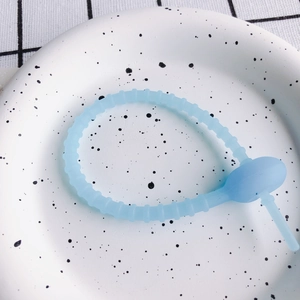 Detailansicht hellblauer Silikon-Kabelbinder mit verstellbarem Ringverschluss auf Teller