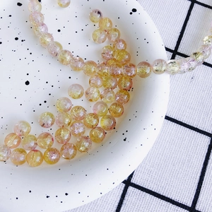 Gros plan de perles en verre de 8mm avec effet craquelé jaune et rose sur un plateau