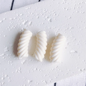 Dettaglio di tre perle a spirale in resina bianca per la creazione di bracciali fai-da-te