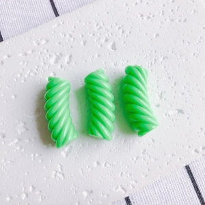 Dettaglio di tre perline a spirale in resina verde brillante per braccialetti fai-da-te