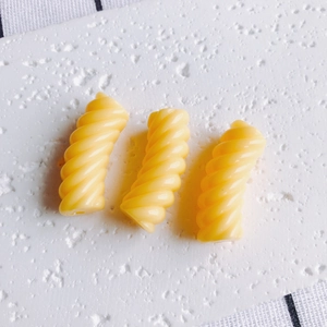 Dettaglio di tre perline a spirale in resina gialla per gioielli fai da te e hobby