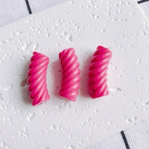 Primo piano di tre perle a spirale in resina rosa per la creazione di gioielli fai-da-te
