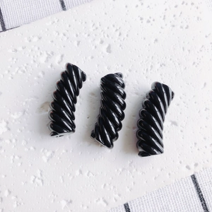 Macro di tre perle a spirale in resina nera per gioielli fai-da-te su pietra bianca