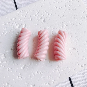 Dettaglio di tre perline a spirale in resina rosa per la creazione di gioielli fai-da-te
