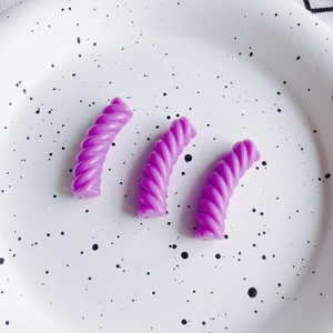 Tre perle a spirale in resina viola per gioielli fai-da-te su fondo bianco macchiato