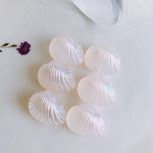 Close-up of iridescent fan-shaped shell charms with pearl luster for DIY jewelry making