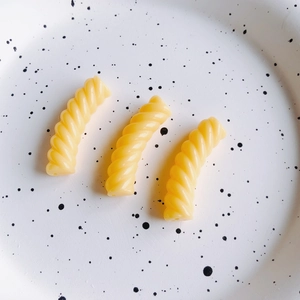 Tre perle a spirale in resina gialla per gioielli fai da te su un piatto bianco macchiato