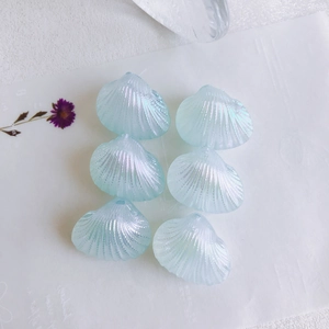 Close-up of six iridescent light blue shell-shaped acrylic beads for DIY jewelry making