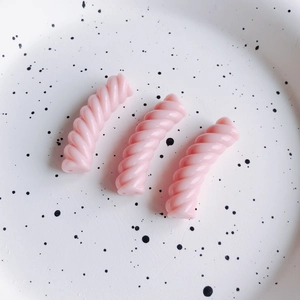 Dettaglio macro di tre perle a spirale in resina rosa chiaro per gioielli fai-da-te