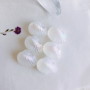 Detailed close-up of iridescent fan-shaped shell beads with rainbow luster for DIY jewelry