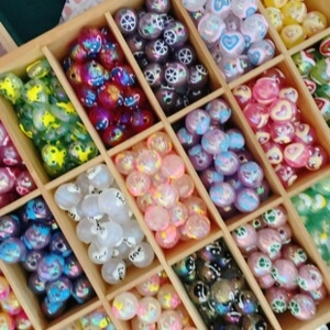 Macro detail of assorted acrylic DIY beads with Love and star patterns in wooden box