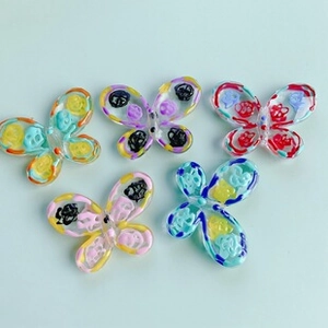 Detailed view of five colorful resin butterfly charms with hand-painted patterns for DIY crafts
