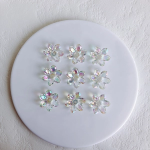 Macro shot of nine translucent aurora acrylic flower charms on a white circular tray
