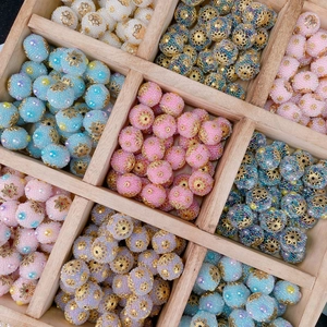 Detailed view of handmade ethnic beads with gold floral caps in a wooden tray