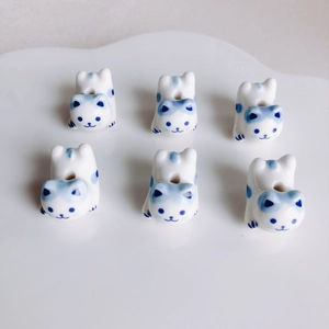 Vista macro di perle di gatto in ceramica bianca e blu per gioielli fai-da-te su piatto