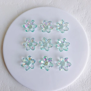 Macro shot of 9 aurora acrylic flower pendants on a white tray for DIY jewelry making