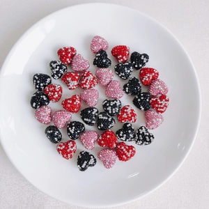 Macro view of heart-shaped rhinestone charms in red, pink, and black for DIY jewelry making