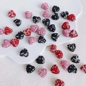 Macro view of heart-shaped rhinestone charms in red, pink, and black for DIY jewelry making