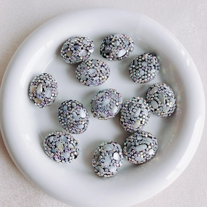 Detailed close-up of 11 colorful floral rhinestone beads and shell inlays for DIY jewelry