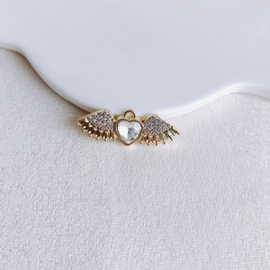 Detailed macro view of a golden heart pendant with wings and clear crystal inlay