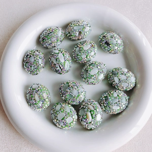 Detailed macro view of green mosaic beads with shell inlay and sparkling rhinestones