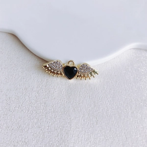 Macro shot of gold-plated wing heart pendant with black gemstone and sparkling crystals