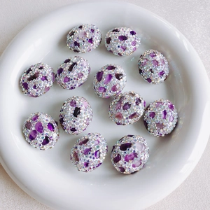 Close-up of 12 oval white DIY beads with purple stones and sparkling crystal rhinestones