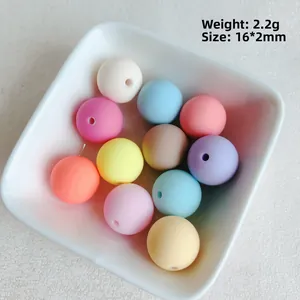 Détail de perles mates macaron de 16mm dans un bol blanc indiquant le poids et la taille