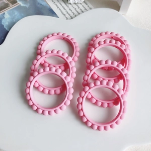 Dettaglio di 8 anelli in silicone rosa con perline per gioielli fai-da-te e artigianato