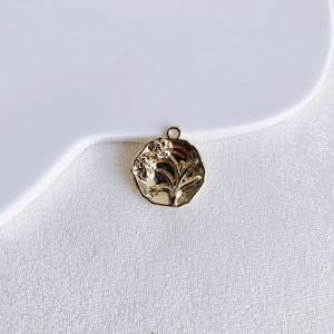 Detailed close-up of a gold embossed flower pendant for DIY jewelry making