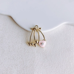 Detailed macro of a heart-shaped cherry pendant with pink enamel and sparkling rhinestone