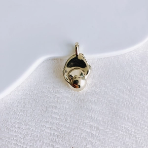Detailed view of irregular organic molten gold pendant on white textured background