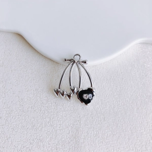 Macro shot of silver cherry heart pendant with black enamel and sparkling rhinestone detail