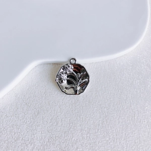 Macro detail of a silver floral relief pendant with elegant scalloped edges on a tray