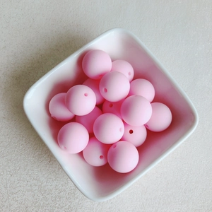 Gros plan de perles en caoutchouc rose macaron mat dans un bol blanc pour bijoux DIY