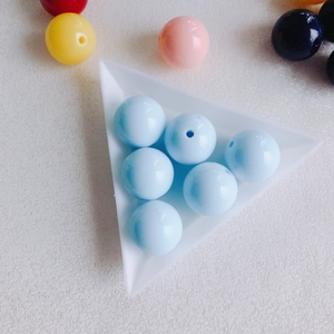 Close-up of colorful round acrylic beads in white tray for DIY jewelry making