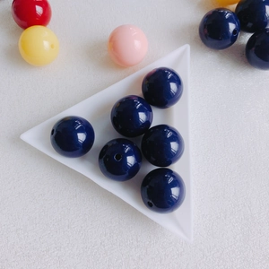 Detail of dark blue acrylic round beads with center hole in a white craft tray