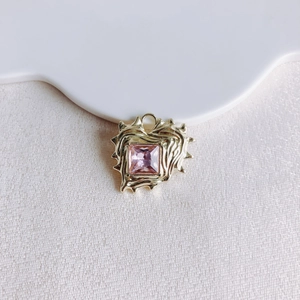 Close-up of irregular heart pendant with square pink zircon in fluid gold frame